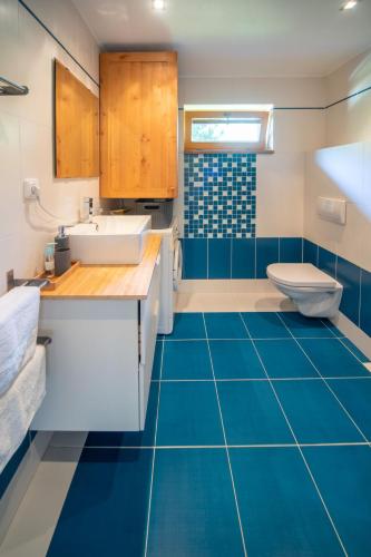 a bathroom with blue flooring and a sink and a toilet at Holiday Home Bila Retreat with Pool by Interhome in Blažejov