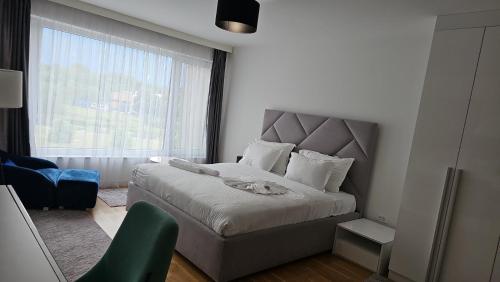 a bedroom with a bed and a chair and a window at Orange Apartment in Sarajevo