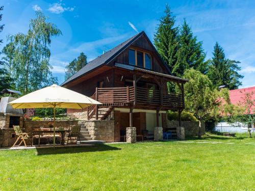 a house with an umbrella and a grass yard at Holiday Home Bila Retreat with Pool by Interhome in Blažejov