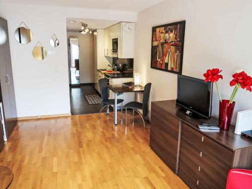 a living room with a television and a table with chairs at Studio A01 by Interhome in Leukerbad