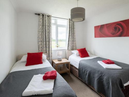 two beds in a room with red pillows at Holiday Home Oak Cottage by Interhome in Shermanbury
