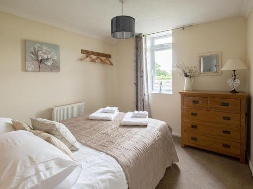 a bedroom with a bed with two towels on it at Holiday Home Oak Cottage by Interhome in Shermanbury