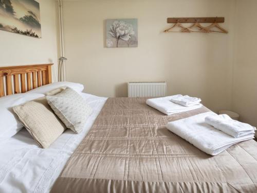a bedroom with a large bed with towels on it at Holiday Home Oak Cottage by Interhome in Shermanbury