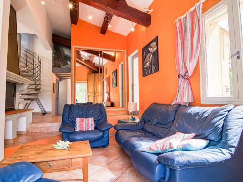 un salon avec des canapés en cuir bleu et un mur orange dans l'établissement Holiday Home Gombaud by Interhome, à Carcès