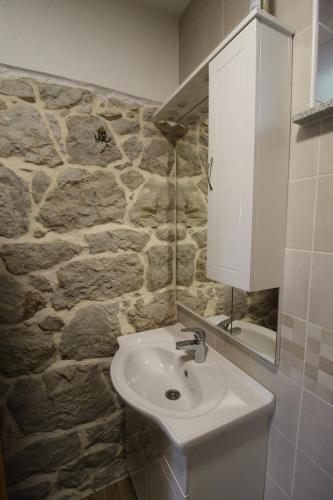 a bathroom with a sink and a stone wall at Studio apartment Lila in Dicmo