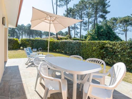 a white table and chairs with an umbrella at Holiday Home Carraou by Interhome in Vielle-Saint-Girons