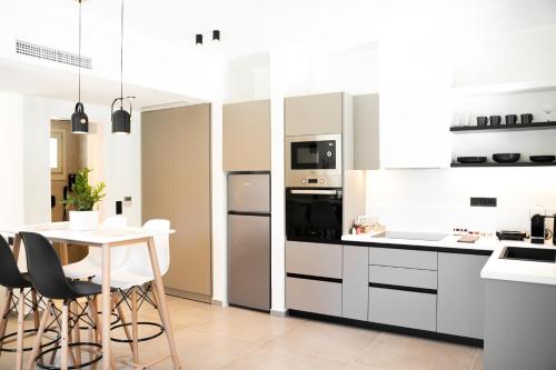 a kitchen with white cabinets and a table with chairs at Apademia Skyros Luxury Residences in Skiros