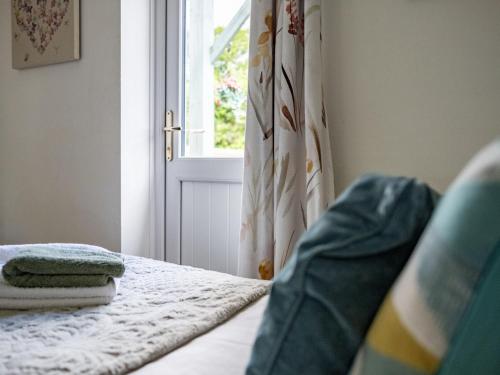 a bedroom with a bed with a window and a curtain at Holiday Home Ash Cottage by Interhome in Shermanbury