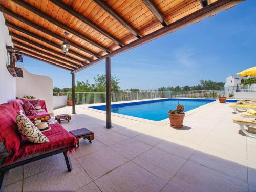 een patio met een rode bank en een zwembad bij Holiday Home Eugênia by Interhome in Paderne