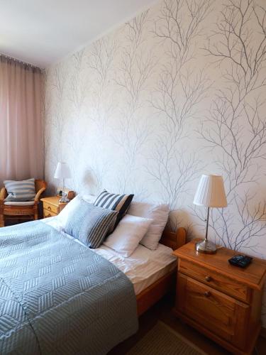 a bedroom with a bed and a wall with tree mural at Apartamenty Vega in Charzykowy
