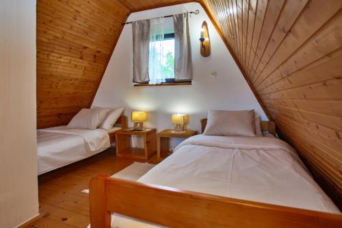 ヴェリカ・プラナにあるChalet Velebitska Kućaのベッド2台と窓が備わる屋根裏部屋です。