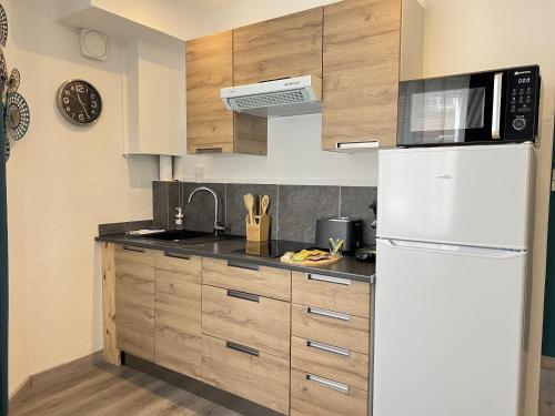 une cuisine avec des armoires en bois et un réfrigérateur blanc dans l'établissement Le Solena, à Calais