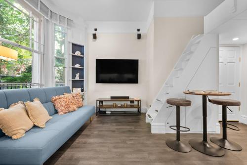 a living room with a blue couch and a tv at VICHY - The Hampstead Star | Prime Location in London