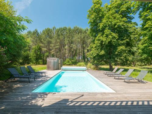 a swimming pool with chaise lounge chairs and trees at Holiday Home La Grange du Belon by Interhome in Saint-Julien-en-Born