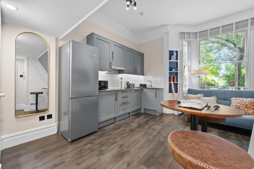 a kitchen with a stainless steel refrigerator and a table at VICHY - The Hampstead Star | Prime Location in London