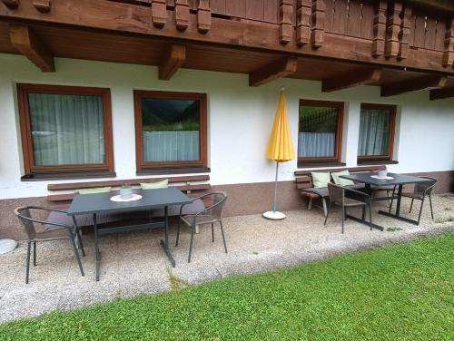 a patio with tables and chairs and a umbrella at Schusslerhof in Sankt Leonhard im Pitztal