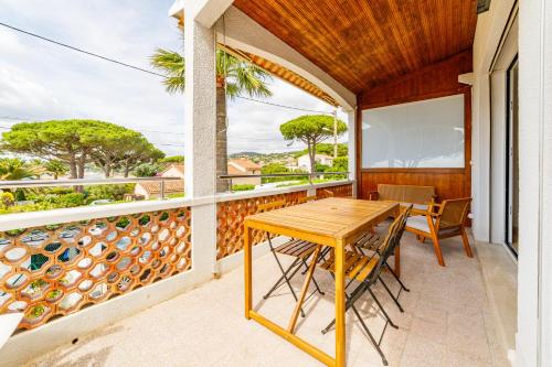 d'une terrasse avec une table et des chaises en bois sur un balcon. dans l'établissement Haut de villa, vue sur mer à Sainte-Maxime, à Sainte-Maxime
