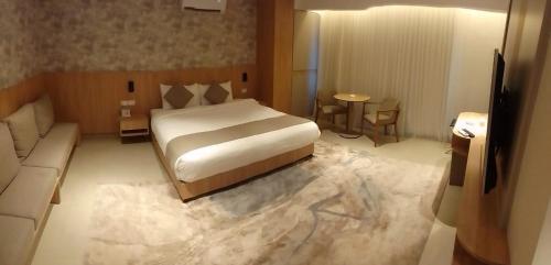 a bedroom with a bed and a living room with a couch at Gardens Hotel in Amman