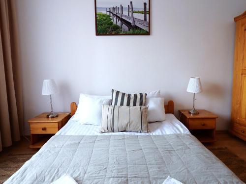 a bedroom with a bed with two lamps and a picture on the wall at Apartamenty Vega in Charzykowy