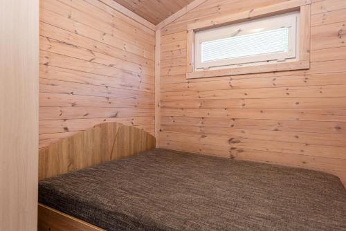 a bed in a wooden room with a window at 83 Pylimas Šventoji in Šventoji