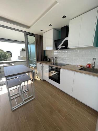 une cuisine avec des armoires blanches et une table et des chaises dans l'établissement Le Bali , terrasse, piscine et parking privé, à Cap d'Ail