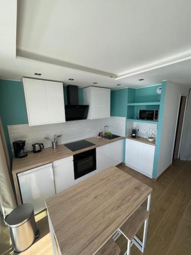 une cuisine avec des armoires blanches et une table en bois dans l'établissement Le Bali , terrasse, piscine et parking privé, à Cap d'Ail