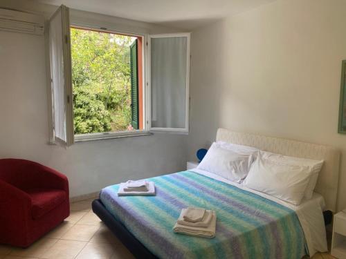 a bedroom with a bed with a red chair and a window at Oasi Verde 1 in Lerici