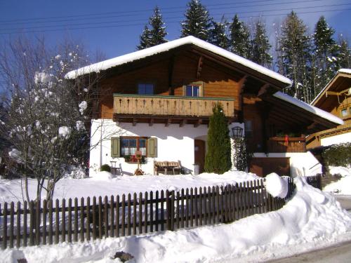 ein Blockhaus im Schnee mit einem Zaun in der Unterkunft Ferienwohnung Wein in Berchtesgaden