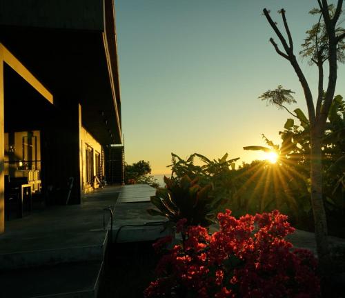 a sunset from a building with flowers in the foreground at 山海高台民宿 M&S nature view house in Chenggong