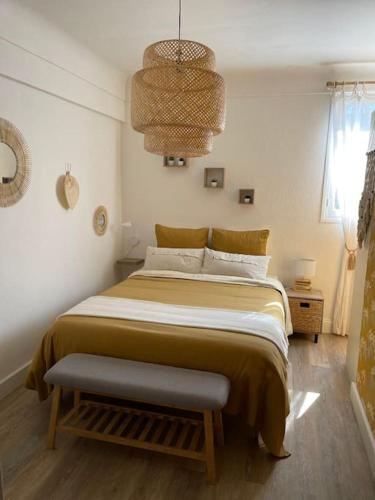 une chambre avec un grand lit et un lustre dans l'établissement Saint Aygulf près de la plage, à Fréjus