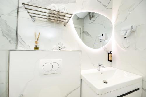 a white bathroom with a sink and a mirror at Rezidenca Panorama Apartments in Vlorë