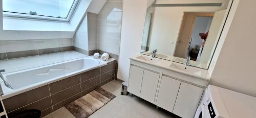 une salle de bain avec une baignoire, un lavabo et un miroir dans l'établissement Maison Moderne proche du centre de Baden, à Baden