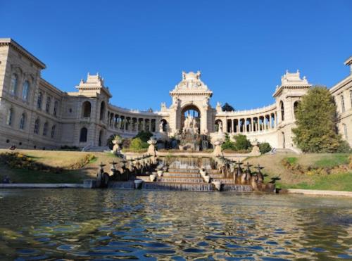 un grand bâtiment avec une fontaine au milieu d'un étang dans l'établissement Marseille Longchamp, à Marseille