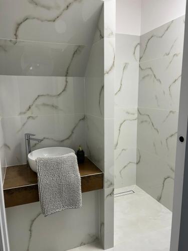 a white bathroom with a sink and marble walls at Apartmán VAJANA Exclusiv & Jacuzzi in Piešťany