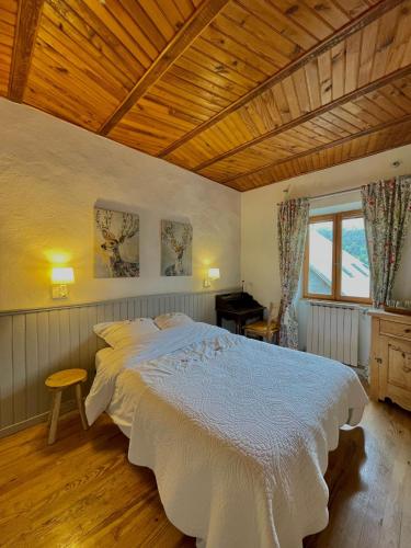 a bedroom with a large white bed with a wooden ceiling at Gîte et chambres d'hôtes "La Tourtette" 12 pers in Le Dévoluy