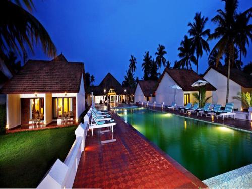 a swimming pool with lounge chairs in a resort at Abad Whispering Palms in Kumarakom