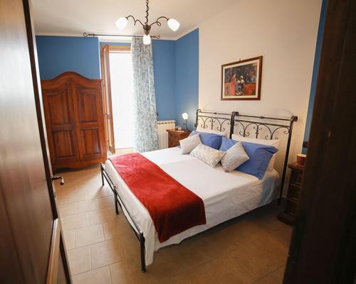 a bedroom with a bed with blue walls and a window at Palazzo Le Muse Apartments in Bevagna