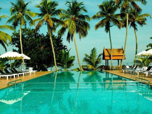 a large swimming pool with palm trees and chairs at Abad Whispering Palms in Kumarakom