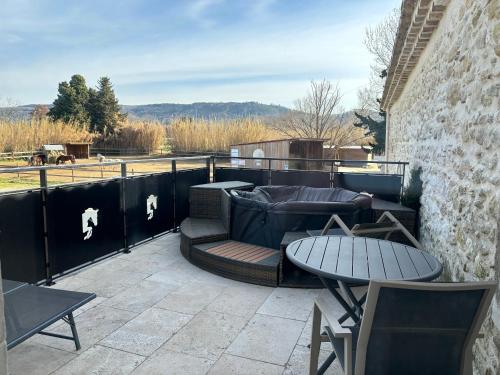 a patio with a table and chairs and a table at La petite plaine in Clansayes