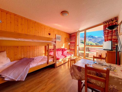 a bedroom with a bunk bed and a desk and a table at travelski home classic - Résidence Grande Masse in Les Menuires