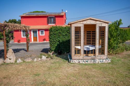 a wooden greenhouse in a yard with a red house at Agriturismo L'Istrice di Giò in Montalto di Castro