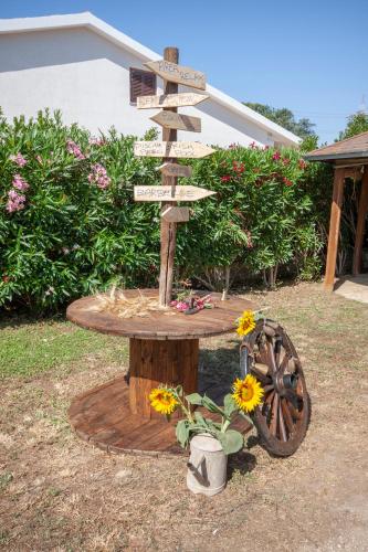 a directional sign on a wooden table with flowers at Agriturismo L'Istrice di Giò in Montalto di Castro
