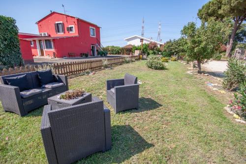 a yard with two chairs and a red house at Agriturismo L'Istrice di Giò in Montalto di Castro