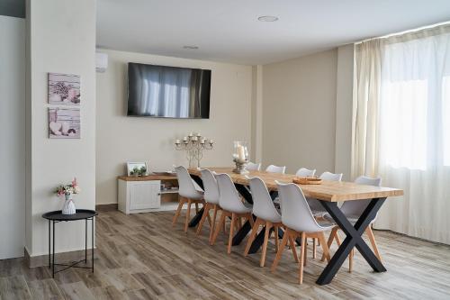 a dining room with a wooden table and white chairs at Villa Canela in Illora