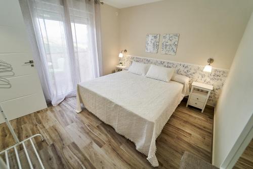 a white bedroom with a bed and a window at Villa Canela in Illora