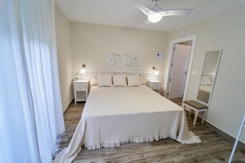 a white bedroom with a large bed with white sheets at Villa Canela in Illora