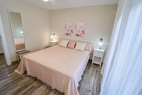 a white bedroom with a bed with pink pillows at Villa Canela in Illora