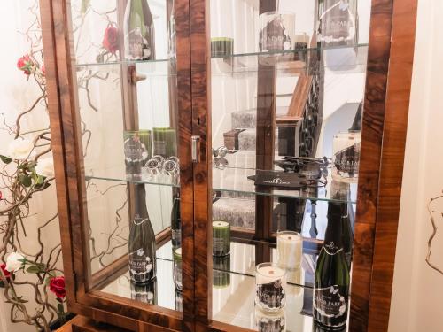 a glass display case with bottles and glasses in it at Quob Park Old House Hotel & Spa in Fareham