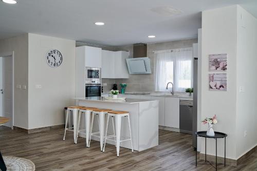 a kitchen with white cabinets and bar stools at Villa Canela in Illora