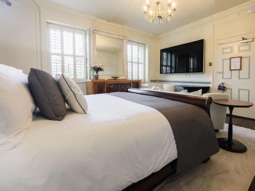 a large bedroom with a large bed and a chandelier at Quob Park Old House Hotel & Spa in Fareham